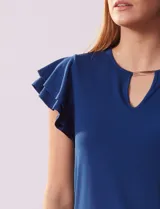 Blusa azul con cuello redondo, escote en V con aplique metálico y mangas cortas con volados en capas.