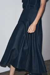 Falda midi de denim azul oscuro, de tiro medio, corte evasé y cierre trasero con cremallera metálica.