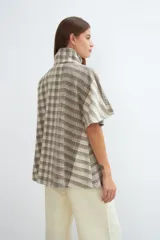 Capa acampanada color beige con manga corta, cierre metálico a la vista, cuello recto, bolsillos con tapa y terminaciones envivadas. Confeccionada en lana fina sin teñir, diseñada exclusivamente por Don Baez.