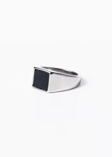 Anillo plateado de acero quirúrgico con piedra negra rectangular en el centro.