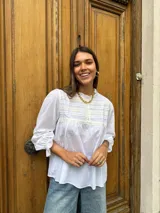Camisa negra de mangas largas con cuello fruncido y detalle de bordado en el pecho.
