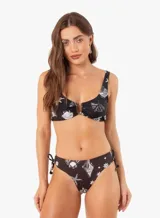 Conjunto de bikini negro con estampado de conchas marinas y estrellas de mar en blanco. El corpiño es de corte clásico con aro y detalle de argolla dorada en el centro. La bombacha es de corte clásico con lazos laterales ajustables.