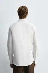 Camisa celeste de algodón con estructura twill, corte regular, cuello solapa, manga larga con puños abotonados y cierre frontal con botones.
