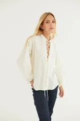 Camisa blanca de popelina de algodón con mangas largas abullonadas y cordones cruzados en los laterales.