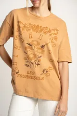 Remera color ocre de corte oversize, con estampado de flores y texto en francés.