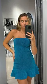 Minivestido turquesa brillante de un solo hombro, corte ajustado y falda con volantes.