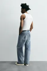Pantalón de jean gris oscuro, corte amplio, con cinco bolsillos, efecto lavado y cierre frontal con cremallera y botón.