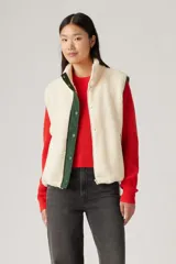 Chaleco color crema de sherpa con cuello alto, cierre frontal con cremallera y ribete de contraste en verde.