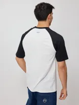 Remera azul marino con mangas raglán color crema y estampado frontal con el logo de Rusty en blanco.