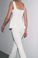 Top blanco de tejido elástico, con escote redondo, tirantes anchos y bajo peplum.