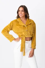 Campera corta color mostaza de terciopelo con cuello clásico, cierre frontal con botones, dos bolsillos de parche en el pecho y cinturón de la misma tela.