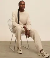 Buzo deportivo femenino confeccionado en microfibra color beige, con cuello redondo, mangas raglán largas y recortes.