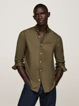 Camisa verde militar de corte regular, con cuello abotonado y mangas largas con puños abotonados. Logo de Tommy Hilfiger bordado en el pecho.