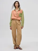 Mono largo de jean celeste con corte holgado, cintura elastizada con cordón ajustable, sin mangas, cuello camisero y cierre frontal con botones. Presenta bordados de motivos playeros en el pecho.