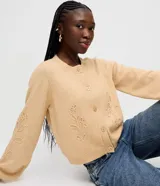 Cardigan de punto color beige, con cuello redondo, cierre frontal de botones, mangas largas con puños acanalados y bordado floral en las mangas y el frente.