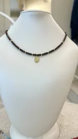 Collar de cristales checos color marrón oscuro con detalles dorados y medalla dorada de la Virgen María.