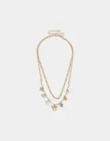 Collar corto dorado de doble cadena con dijes de cerámica, perlas, corazón y moño.
