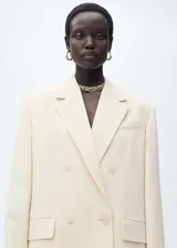 Blazer color crema con cuello de solapa, doble botonadura frontal, corte recto y mangas largas con puños abotonados. Prenda de la colección de evento.