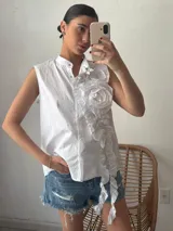Camisa blanca sin mangas con cuello mao y volados en el frente.