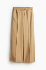 Pantalón palazzo color beige con cintura elástica fruncida y cordón ajustable. Cuenta con bolsillos laterales discretos y bolsillos traseros decorativos.