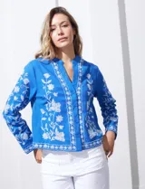 Chaqueta de algodón bordada, color azul con bordado floral blanco, con cuello a la base y escote en V, abertura central con botón.