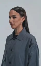 Campera gris con broches en el delantero, forrada con red, múltiples bolsillos con detalles en réflex y puños elásticos en las mangas. Confeccionada en textil liviano 100% poliéster y calce oversize.