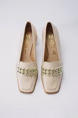 Zapato de cuero color beige con textura croco, taco cuadrado y detalle de apliques dorados.