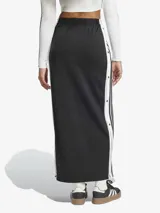 Falda larga Adidas Adicolor, color negro, de tejido de tricot brillante. Diseño inspirado en el pantalón deportivo Adibreak, con corte holgado, largo maxi y botones a presión laterales con logo de la marca. Confeccionada con materiales 100% reciclados.