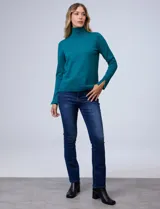 Polera de punto fino marca Nienty, color blanco, con cuello alto volcado y mangas largas con detalle de tajo en los puños.