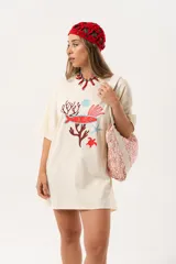 Remerón de algodón color crema con estampado de motivos marinos en tonos rojo y celeste, de corte oversize y largo a la rodilla.