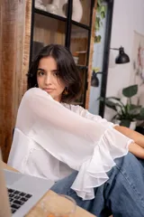 Blusa blanca de gasa con volados en el frente y mangas acampanadas.