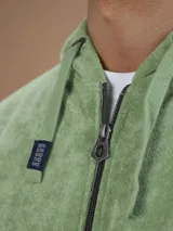 Campera con capucha de toalla de algodón color verde azulado, con cierre frontal y bolsillos laterales.