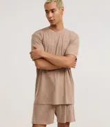 Conjunto de pijama corto para hombre, compuesto por una remera de manga corta con cuello redondo y un short con cintura elástica y cordón de ajuste. El tejido es malla flameada con efecto mezcla en tono verde claro.