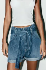 Bermuda de jean celeste, tiro alto, corte paper bag, con trabillas y cinturón lazada. Tiene bolsillos laterales y traseros.