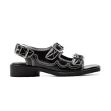 Sandalias bajas negras de cuero sintético, con dos tiras anchas sobre el empeine y una tira trasera con hebilla. Presentan costuras blancas en contraste y suela track.