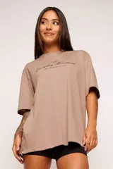 Remera color beige con estampado de texto en el frente, corte amplio y mangas cortas.