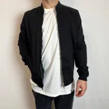 Chaqueta bomber negra con cierre frontal y bolsillos laterales.