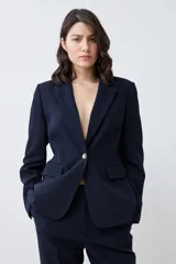 Blazer negro de corte clásico con solapas de muesca, cierre frontal con un botón y bolsillos con solapa.