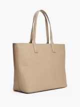 Cartera tote Tommy Hilfiger color beige con sutil acabado granulado. Cuenta con cierre de cremallera, dos asas superiores, compartimento principal, bolsillo interior con cremallera, forro con la inscripción de Tommy Hilfiger y logo de Tommy Hilfiger en la parte delantera.