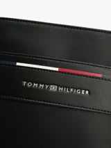 Bandolera negra de Tommy Hilfiger con acabado texturizado, cierre de cremallera, correa ajustable, compartimento principal, bolsillo interior con cremallera, logo metálico de Tommy Hilfiger en la parte delantera y detalles distintivos de la marca.