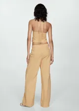 Pantalón color beige de tiro medio y corte ancho, con bolsillos laterales, bolsillos cargo y bolsillos de parche en la parte posterior.