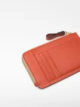 Monedero marrón de cuero con cierre de cremallera y tarjetero en la parte trasera.