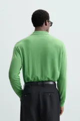 Polo verde de punto ligero tejido en hilatura de lana. Cuello solapa con cierre frontal de botonadura. Manga larga. Acabados en rib.