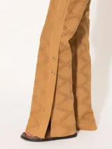 Pantalón flare color camel de broderie con aberturas en botamangas cerradas con broches dorados. Presenta bolsillos delanteros diagonales con vivos en cuero al tono.