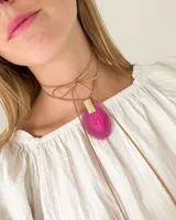 Collar con piedra color fucsia de forma orgánica, con cordón de sujeción en tono natural.