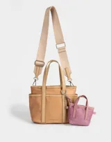 Cartera tipo tote color beige, de tela deportiva, con doble asa corta y correa larga regulable y desmontable. Tiene un bolsillo lateral con forma de pouch.