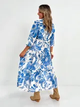 Vestido largo camisero con estampado floral en tonos rosados y blancos, con cuello camisero, manga 3/4 y falda escalonada. Incluye cinturón fino de soga.