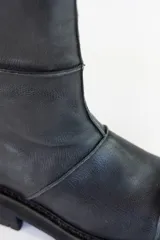 Bota de caña media color negro, de cuero, con suela track y puntera redondeada.