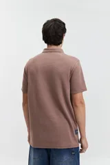 Polo marrón con textura y logo bordado.