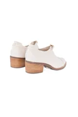 Zapato de cuero texturizado color blanco hueso, con punta cuadrada, detalle de hebilla dorada y taco de madera.
